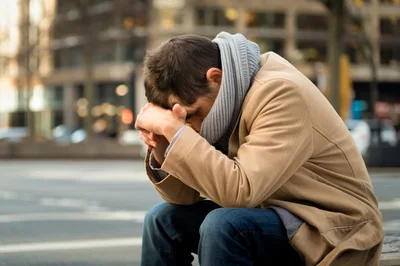 Depressed Man Sitting Alone On City Street