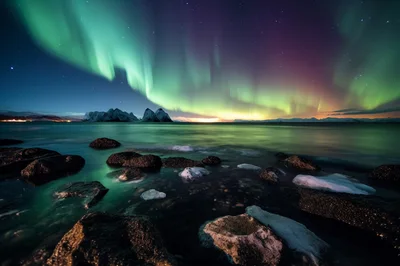 Aurora Borealis Over Snowy Mountains And Rocky Coastline