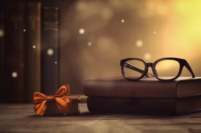Eyeglasses Resting On Stacked Books With Decorative Bow