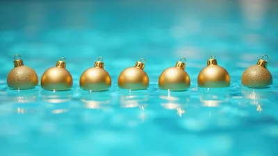 Seven Golden Christmas Ornaments Floating In Blue Water