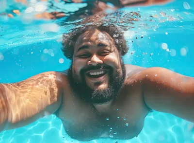 Happy Man Swimming Underwater In A Bright Pool