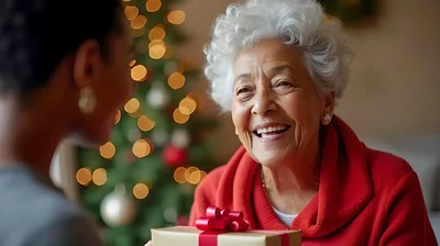 Granddaughter Giving Christmas Gift To Smiling Grandmother