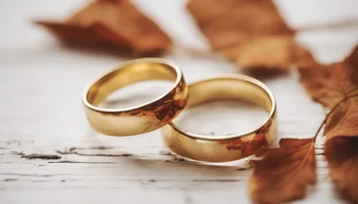 Two Gold Wedding Rings On A Rustic Wooden Surface