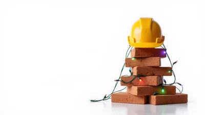 Yellow Hard Hat On Stacked Bricks With Christmas Lights