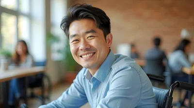 Smiling Asian Man In Wheelchair Working In Office
