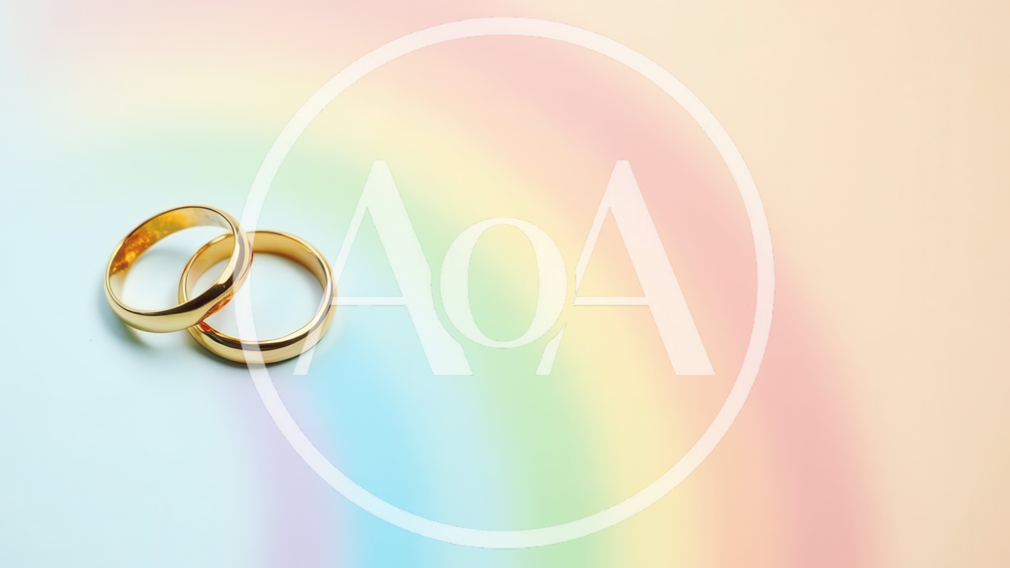 Two Gold Wedding Rings On A Pastel Rainbow Background