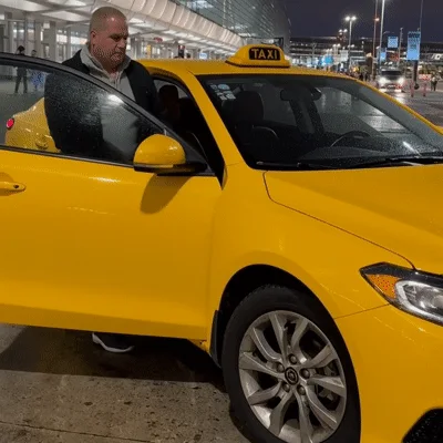 Man Entering Yellow Taxi Cab At Airport Terminal