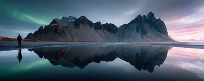 Lone Hiker Standing Before Vestrahorn Mountain In Iceland