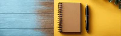 Spiral Notebook and Pen on Yellow and Wooden Background