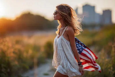 Young Woman Walking With American Flag At Sunset