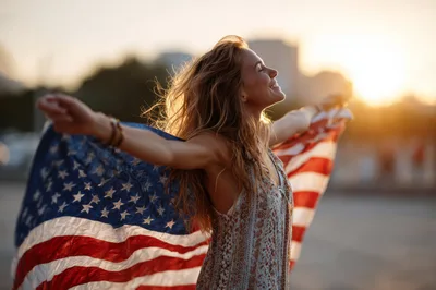 Young Woman Celebrating With American Flag At Sunset
