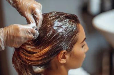 Professional Hairdresser Applying Dye To Client Hair