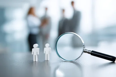 Magnifying Glass Focusing On Small Human Figurines