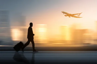 Businessman Walking With Luggage Near Departing Airplane