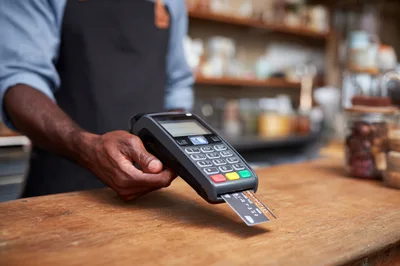 Barista Holding Payment Terminal With Inserted Credit Card