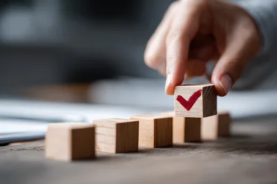 Hand Placing Wooden Block With Red Checkmark