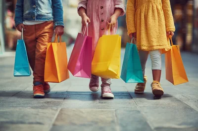 Three Children Walking With Colorful Shopping Bags