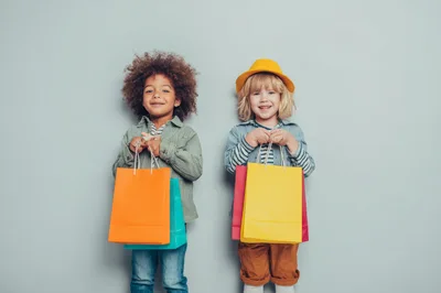 Two Happy Children Holding Colorful Shopping Bags