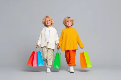Two Happy Children Holding Colorful Shopping Bags