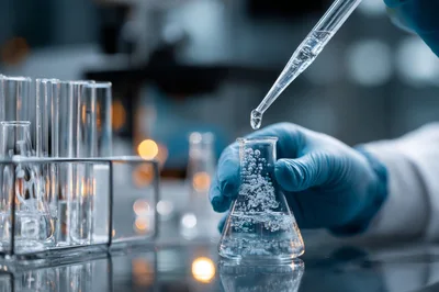 Scientist Adding Liquid To Erlenmeyer Flask In Laboratory