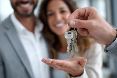 Real Estate Agent Handing Over House Keys To Couple