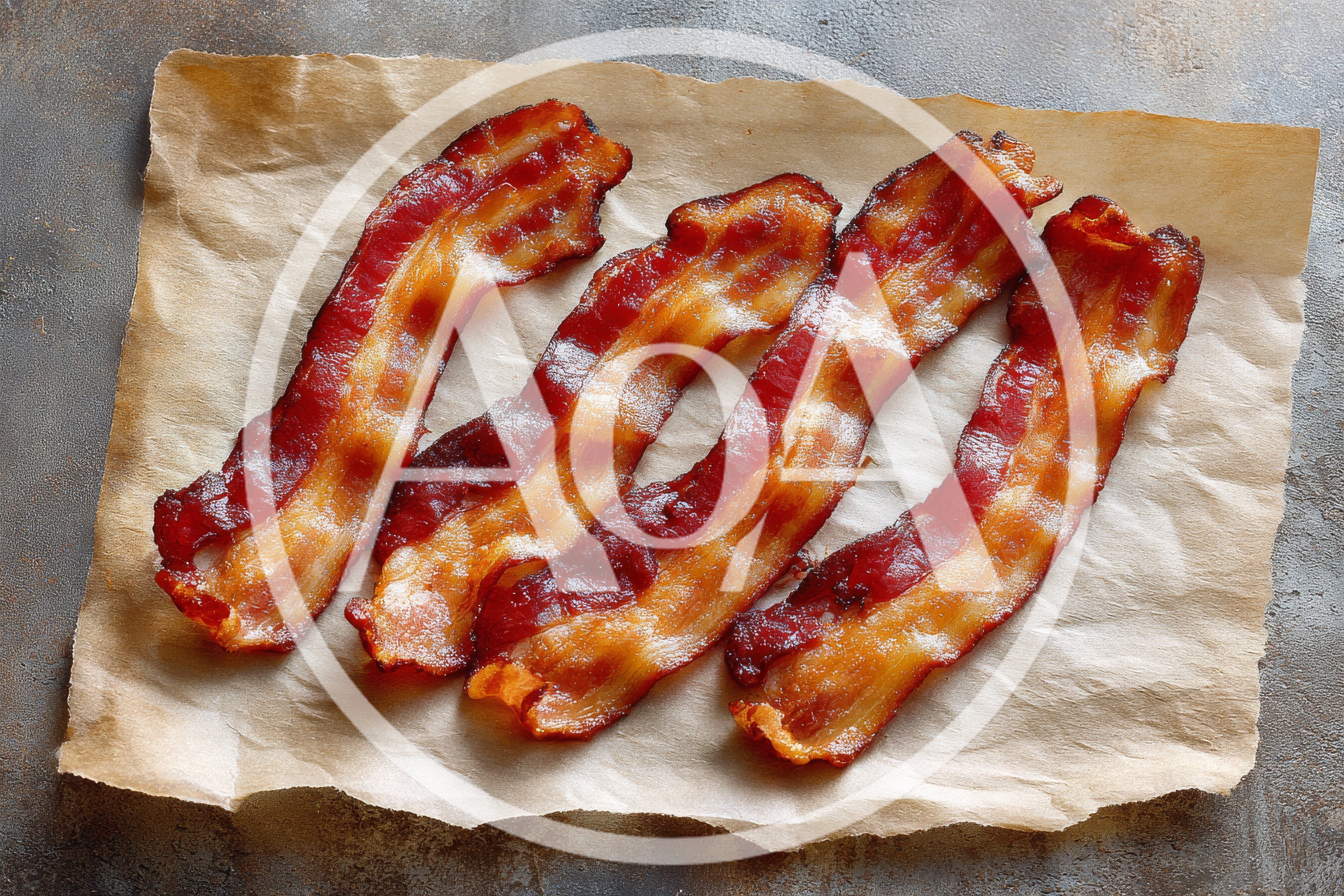 Four Strips Of Crispy Cooked Bacon On Parchment Paper