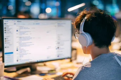 Young Man Working On Computer With Headphones
