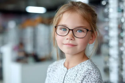 Young Girl Trying On New Glasses In Optical Store