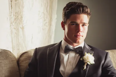 Handsome Groom Sitting On Sofa In Formal Suit