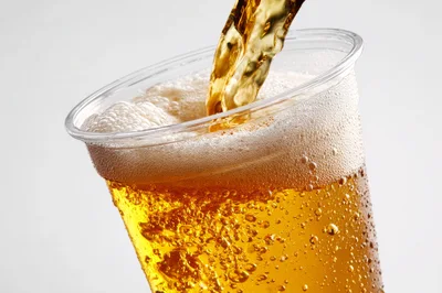 Golden Beer Pouring Into A Clear Plastic Cup