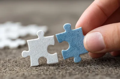 Hand Connecting Two Puzzle Pieces On Concrete Surface
