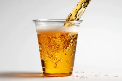 Golden Beer Pouring Into A Clear Plastic Cup