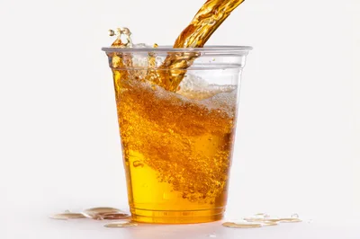 Golden Liquid Pouring Into A Clear Plastic Cup