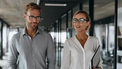 Professional Colleagues Walking And Talking In Modern Office Hallway