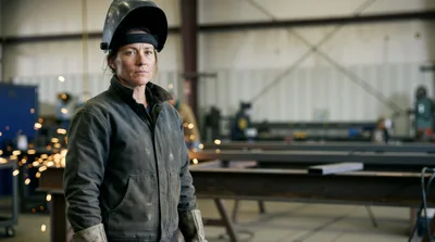 Female Welder Standing In Industrial Workshop