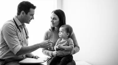 Pediatrician Consulting With Mother And Baby In Clinic