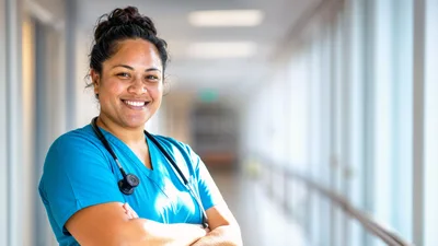Smiling Female Nurse Standing In Hospital Corridor