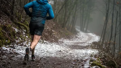 Trail Runner Running Through Snowy Forest Path