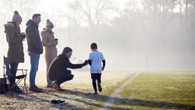 Parents Encouraging Young Soccer Player On Cold Morning
