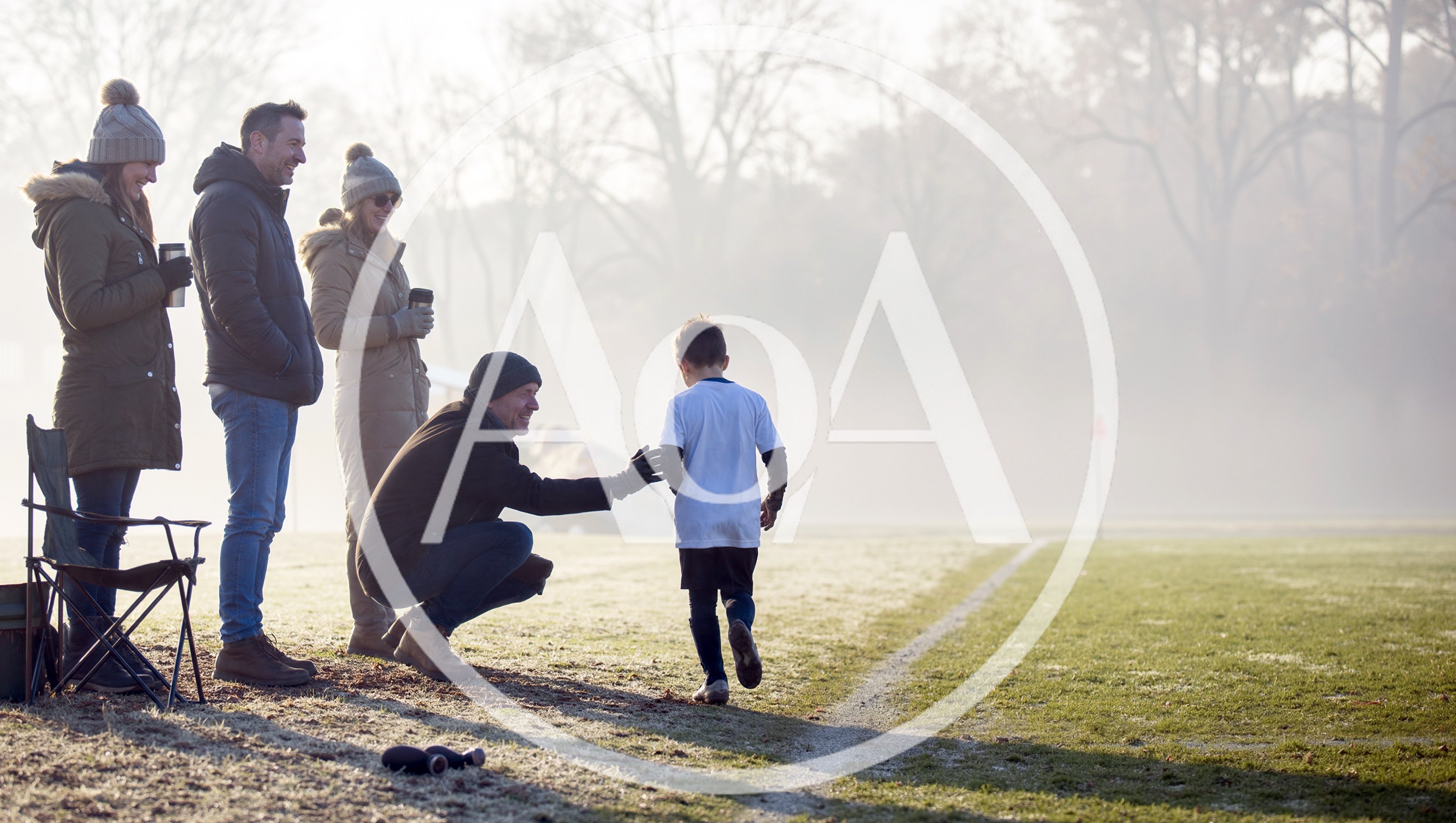 Parents Encouraging Young Soccer Player On Cold Morning