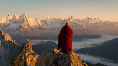 Buddhist Monk Standing On Mountain Peak At Sunrise