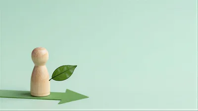 Wooden Peg Doll Standing On Green Paper Arrow