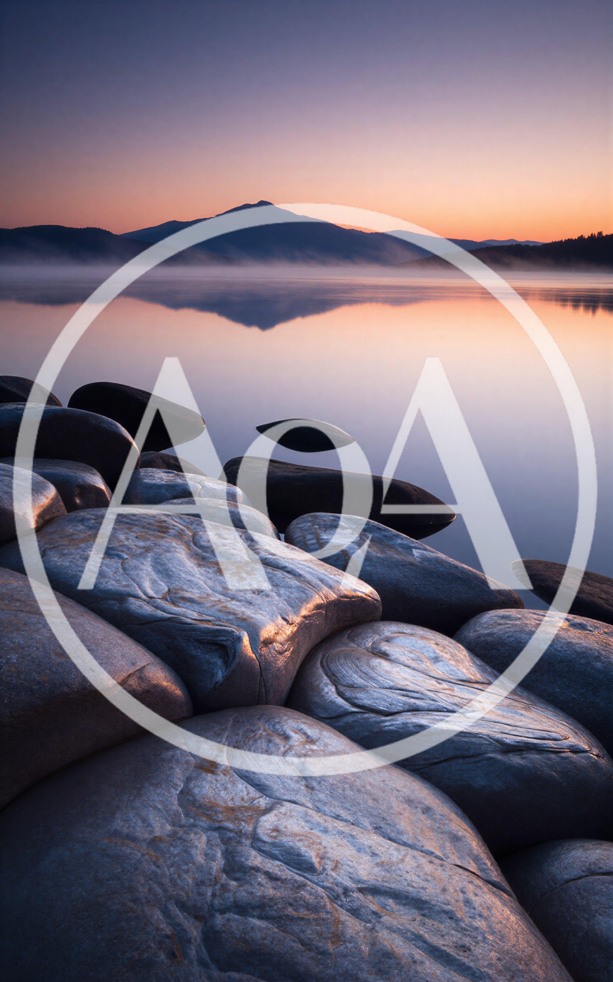 Sunrise Over A Calm Lake With Large Smooth Rocks