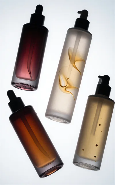 Four Cosmetic Bottles With Dropper Caps On White Background