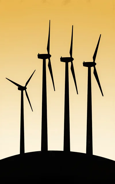 Silhouette Of Four Wind Turbines Against A Golden Sky