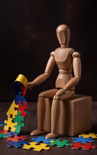 Wooden Mannequin Holding Colorful Puzzle Pieces