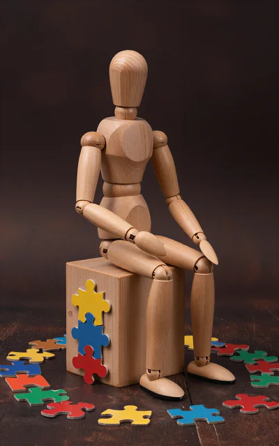 Wooden Mannequin Sitting on Block with Puzzle Pieces