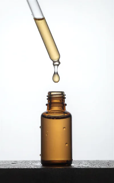Dropper Dispensing Golden Serum Into Amber Glass Bottle