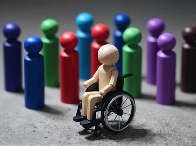 Wooden Figure In Wheelchair Surrounded By Colorful Peg Dolls