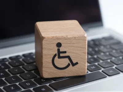 Wooden Block With Disability Symbol On Laptop Keyboard